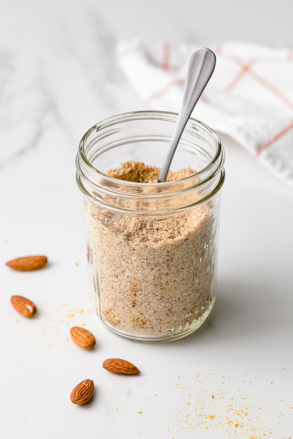side angle view of almond parmesan in a mason jar with spoon.