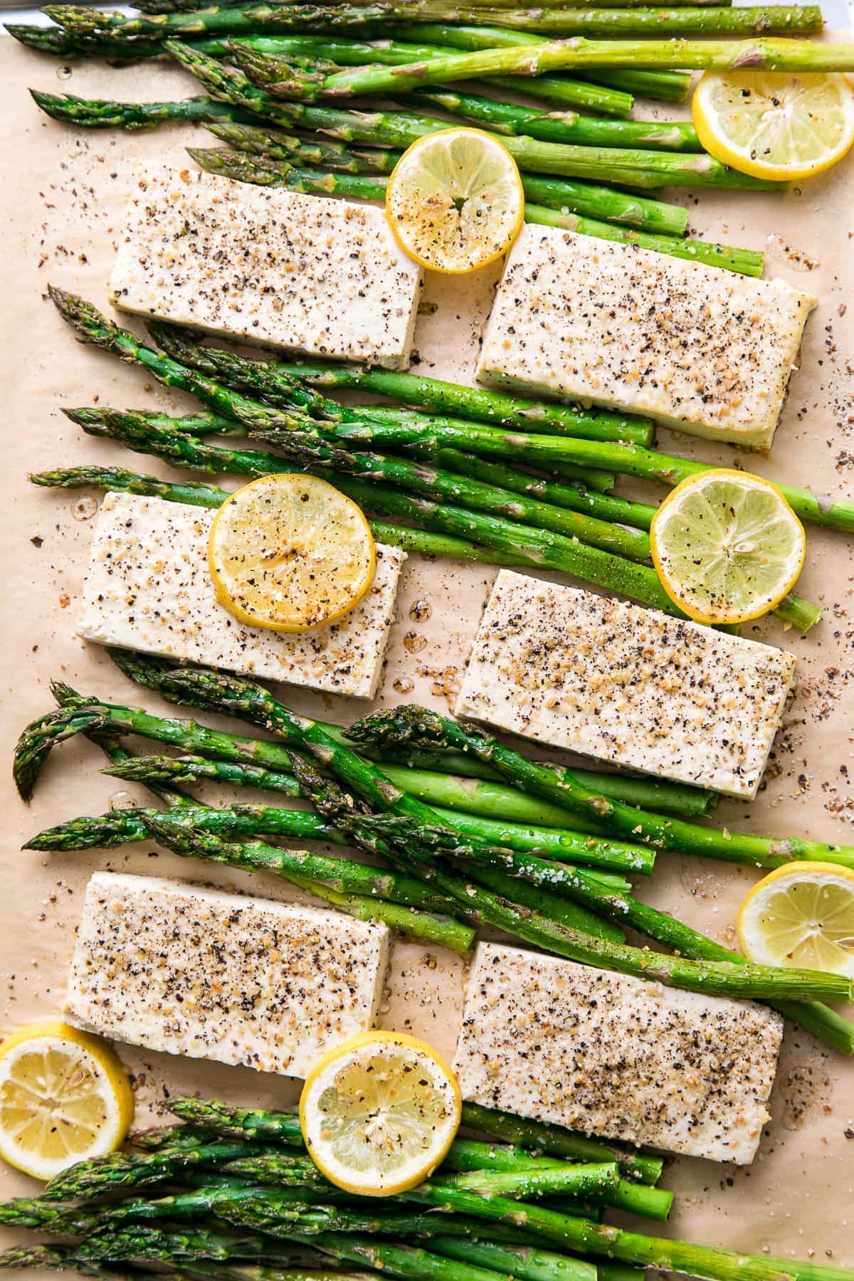 top down view of freshly baked lemon pepper tofu with asparagus on sheet pan.