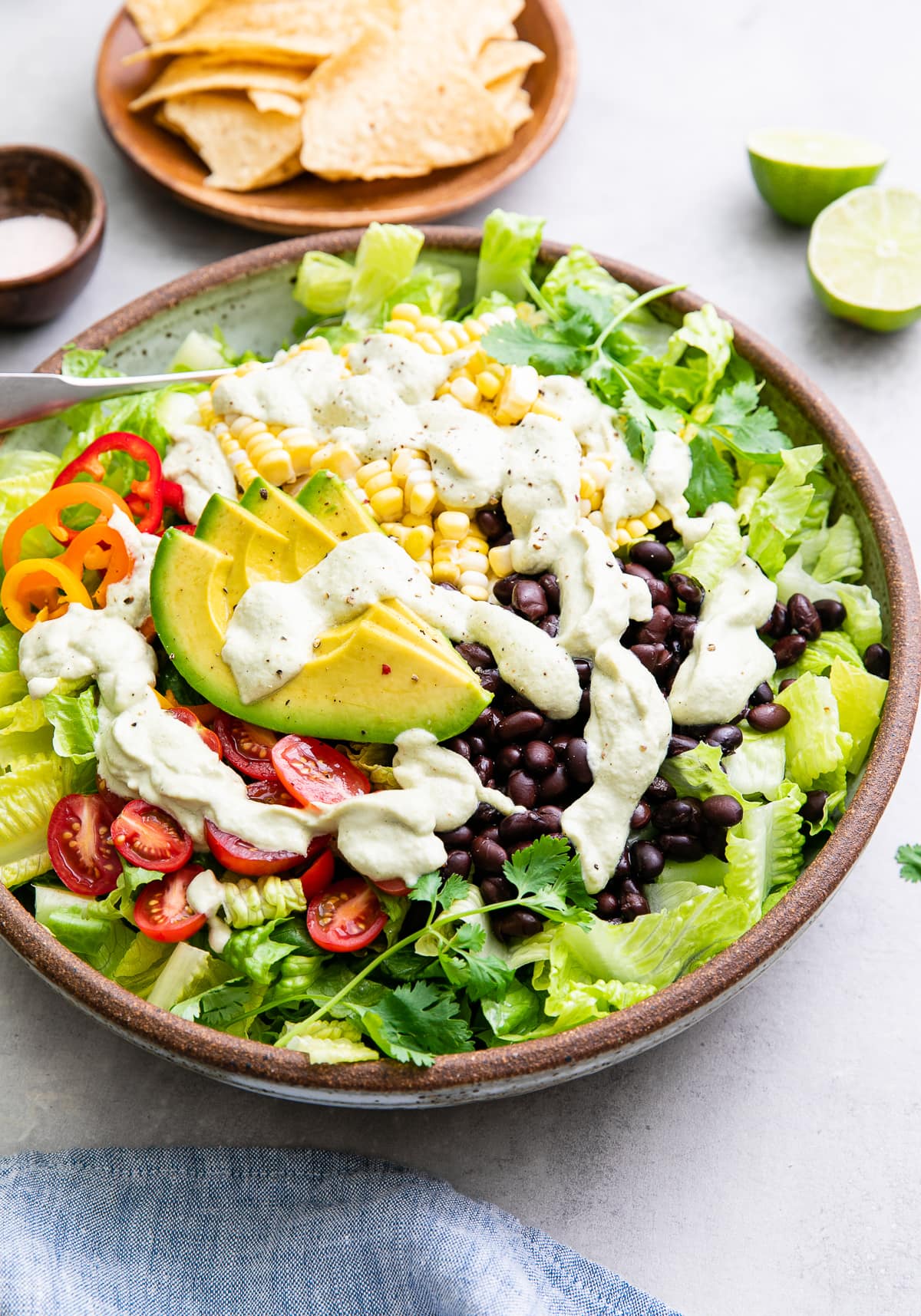 side angle view of freshly made southwestern salad in a bowl with items surrounding.