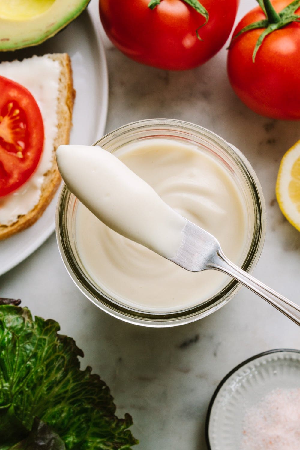 homemade vegan mayonnaise in a mason jar with butter knife ready to spread