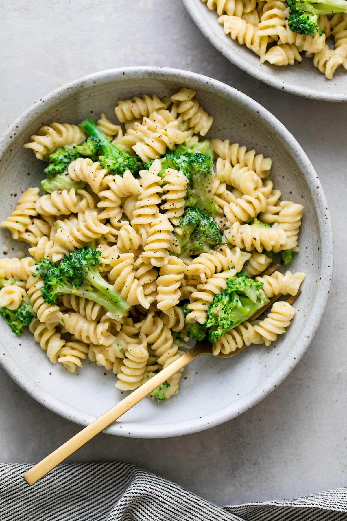 top down view of creamy broccoli pasta with gold spoon.