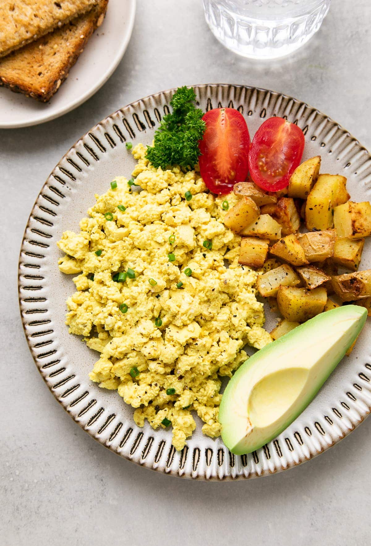 side angle view of a small plate with tofu scramble and items surrounding.