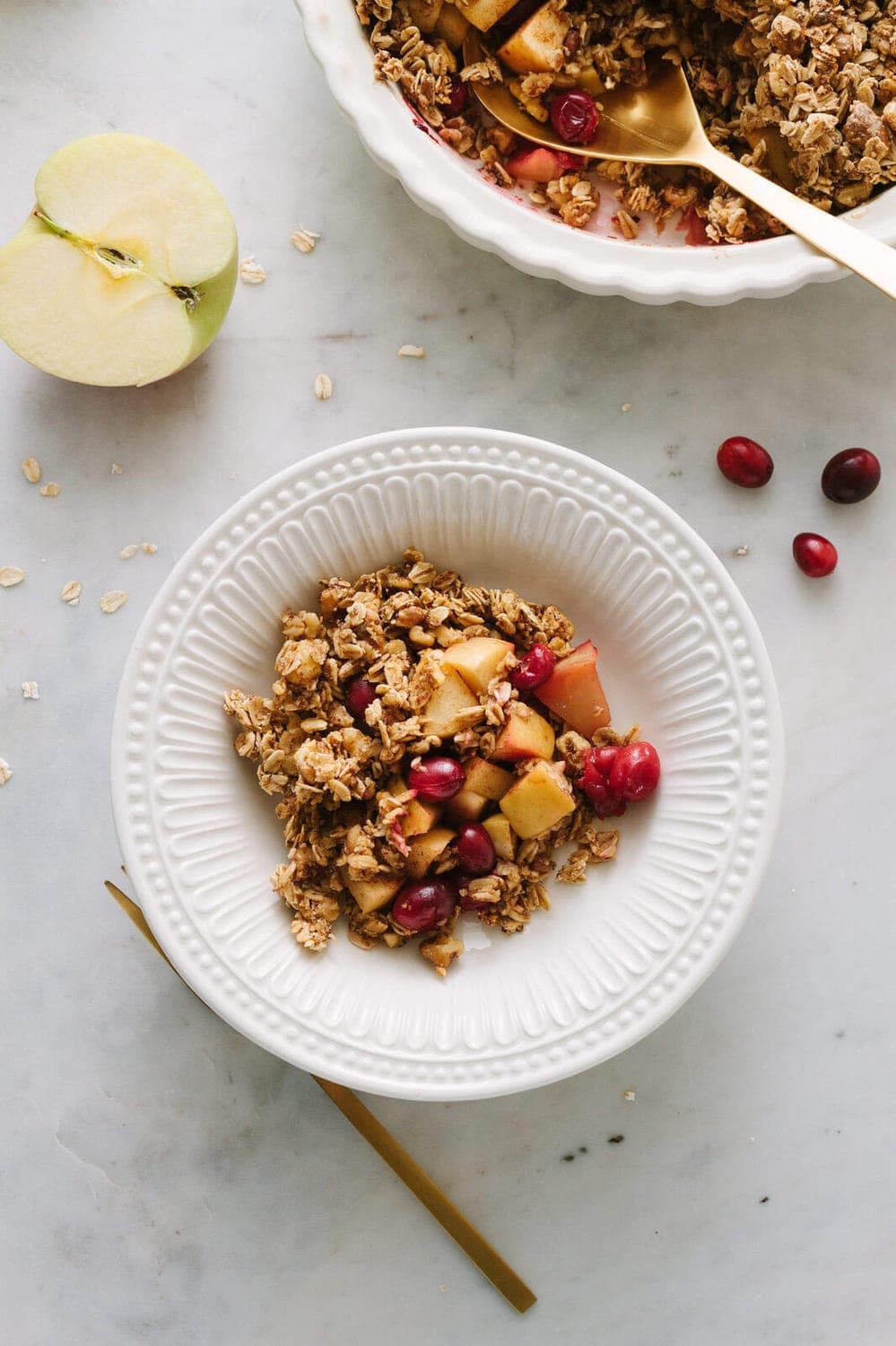 healthy apple cranberry crisp in a white bowl with fork