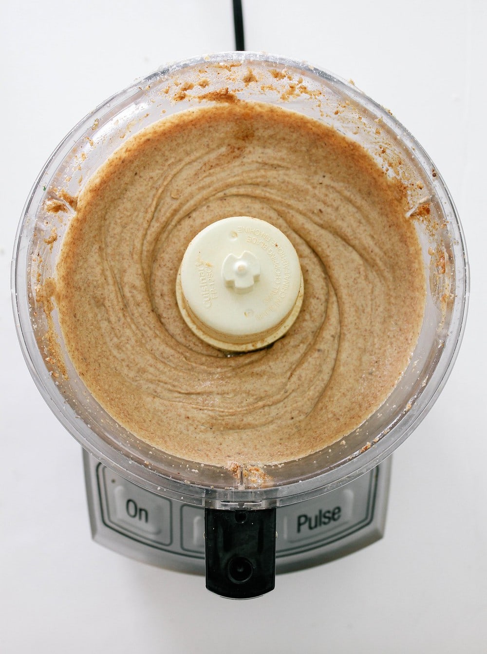 top down view of homemade almond butter finished processing in a food processor, result is smooth creamy almond butter